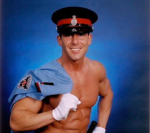 Canadian Storm - Miguel Storm in police officer costume Professional photo of performer Miguel Storm smiling in his police costume with shirt draped over his shoulder
